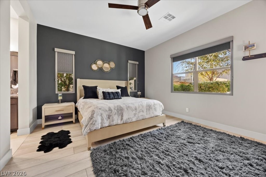 4262 Swift Street Las Vegas, NV 89135 - Photo 27 of 75 Bedroom featuring multiple windows, an accent wall, ceiling fan, and light wood-style flooring