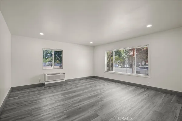 a view of an empty room with a window and wooden floor