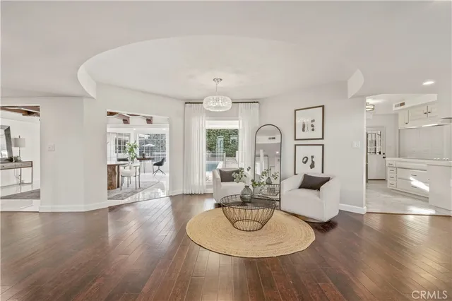 a living room with couches and a dining table with wooden floor