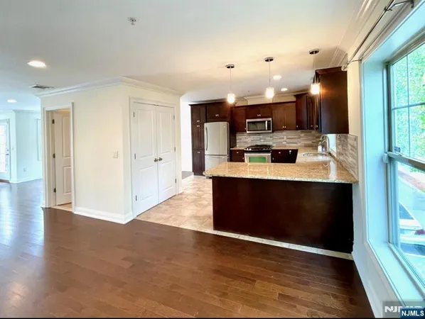 a view of kitchen with kitchen island stainless steel appliances a sink cabinets and wooden floor