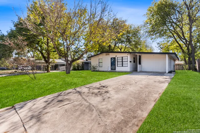 a view of house with a big yard and large trees