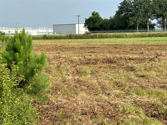 a view of a field of grass and a building with trees in the background
