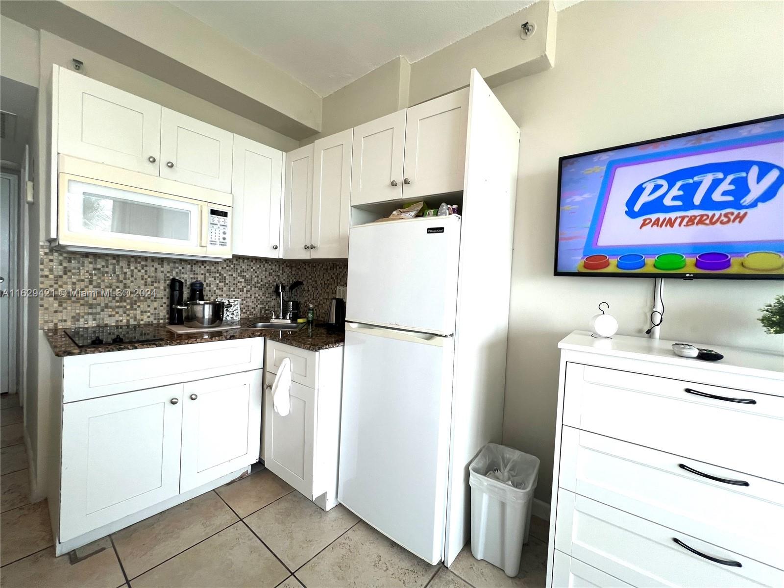 6345 Collins Avenue, Unit 635 Miami Beach, FL 33141 - Photo 13 of 28 a kitchen with a refrigerator sink and cabinets