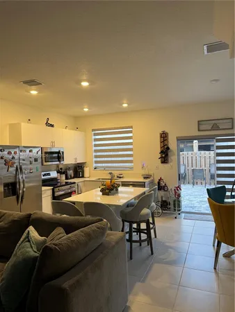 a living room with couches and kitchen view with wooden floor