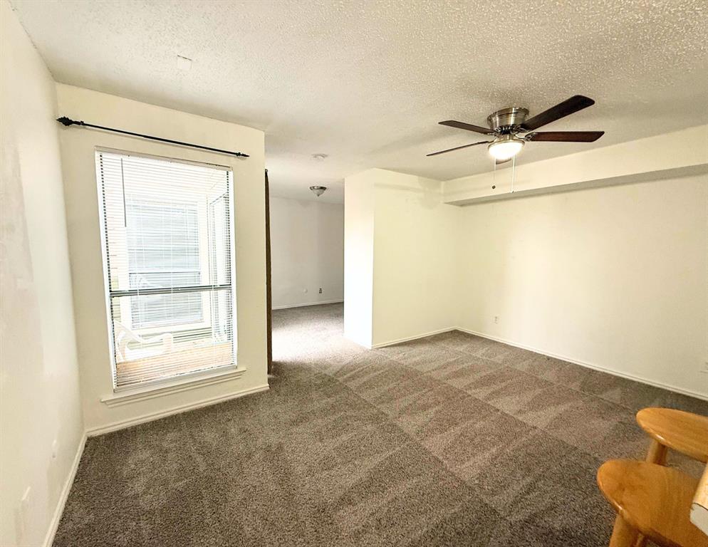 9803 Walnut Street, Unit 308 Dallas, TX 75243 - Photo 12 of 13 Carpeted empty room featuring baseboards, a textured ceiling, and a ceiling fan