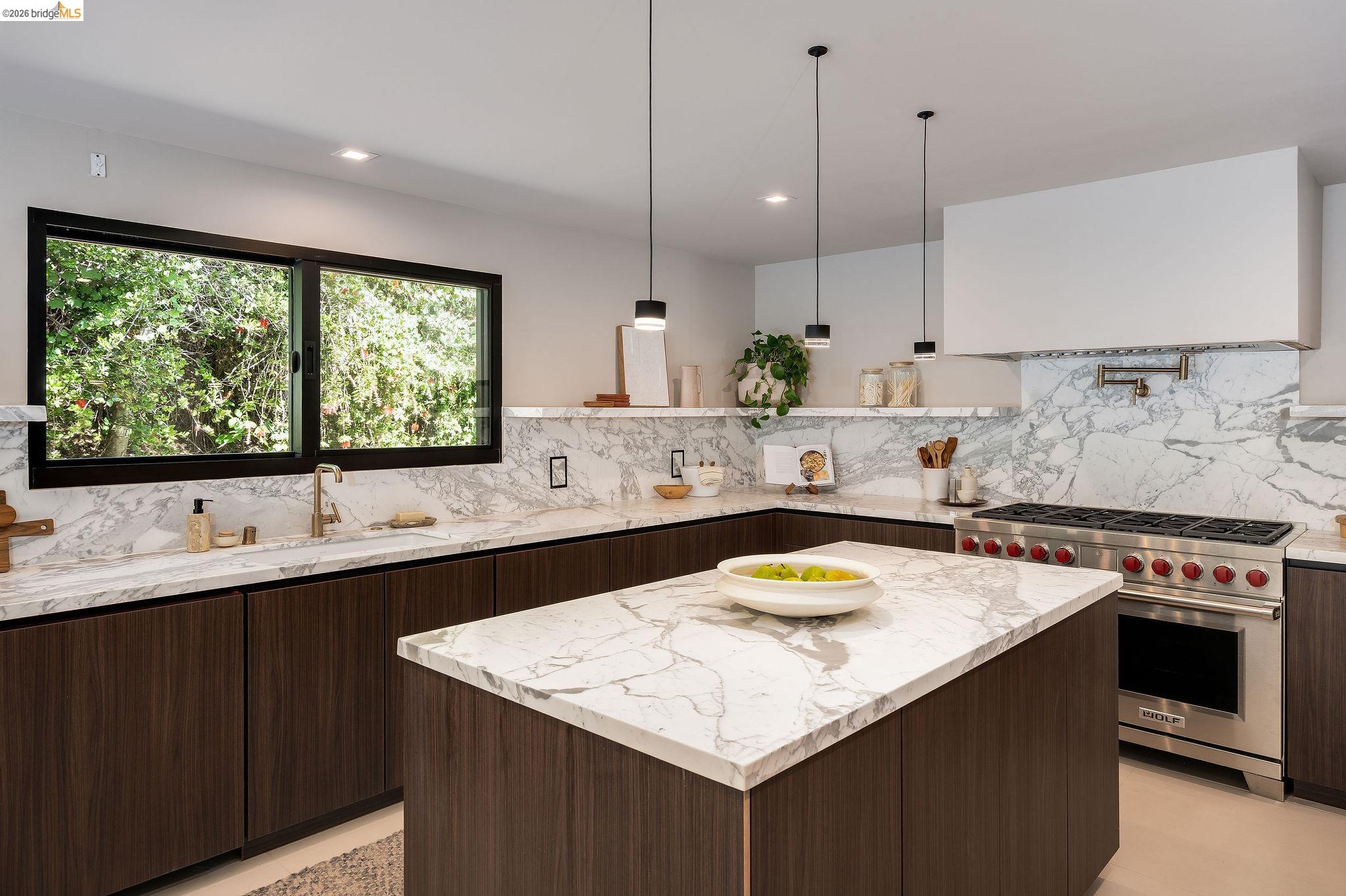 5645 Bacon Road Oakland, CA 94619 - Photo 35 of 94 Spacious kitchen featuring an island with a waterfall countertop, dark wood-finish cabinetry, a professional-grade stainless steel range, and a full-height backsplash