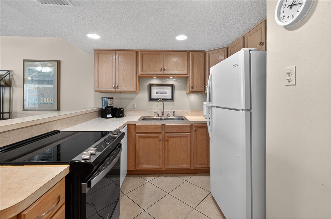 14810 Windward Drive, Unit 402 Corpus Christi, TX 78418 - Photo 5 of 39 a kitchen with refrigerator cabinets and a sink