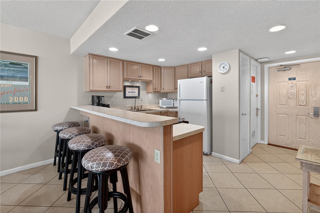 14810 Windward Drive, Unit 402 Corpus Christi, TX 78418 - Photo 8 of 39 a kitchen with stainless steel appliances granite countertop a refrigerator a sink a stove a dining table and chairs