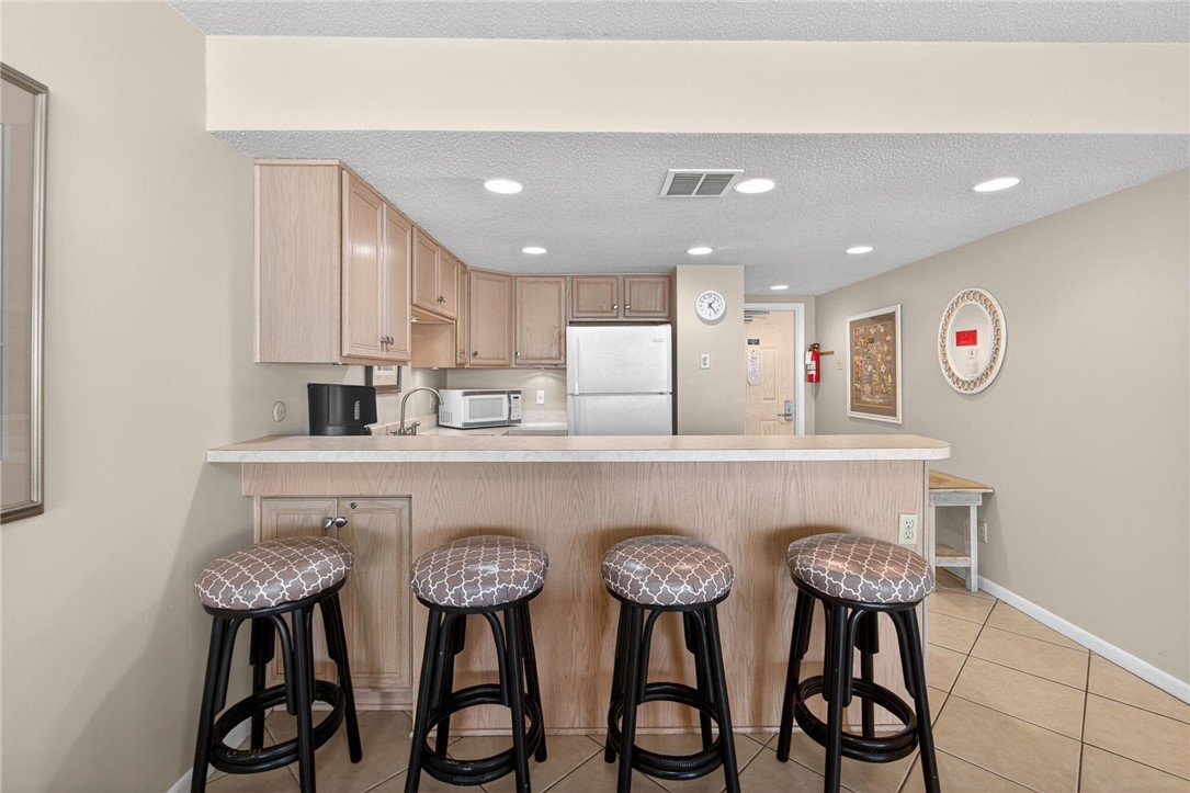 14810 Windward Drive, Unit 402 Corpus Christi, TX 78418 - Photo 9 of 39 a kitchen with stainless steel appliances kitchen island granite countertop a dining table chairs and sink