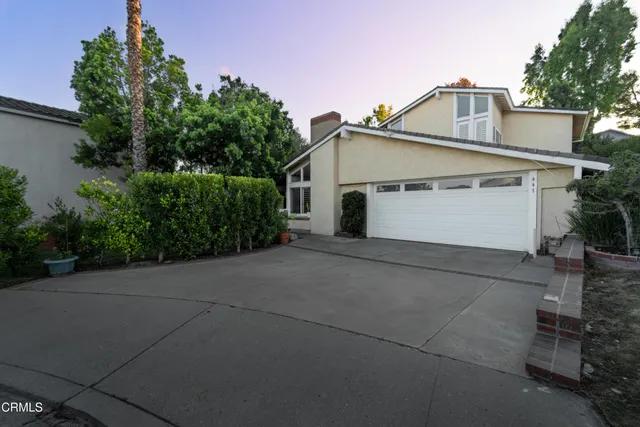 a view of a white house with a yard and plants