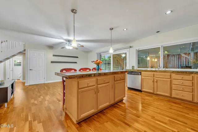 a kitchen with kitchen island granite countertop a sink cabinets and wooden floor