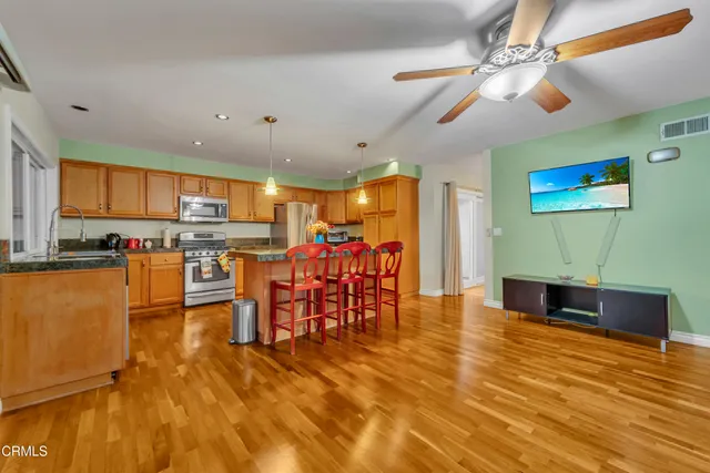 a living room with stainless steel appliances furniture and a kitchen view