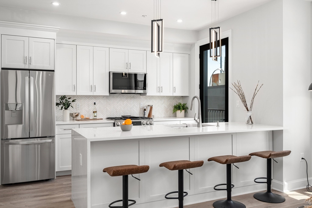 a kitchen with stainless steel appliances a sink a stove a refrigerator and cabinets