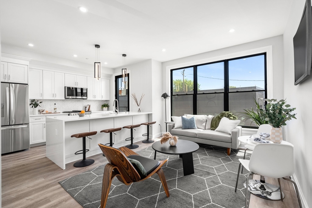 523 2nd Street, Unit 303 Everett, MA 02149 - Photo 2 of 11 a living room with furniture and kitchen view with wooden floor