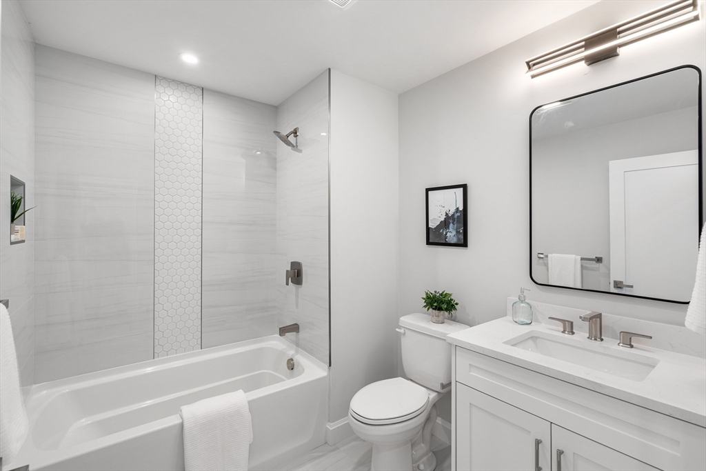 523 2nd Street, Unit 303 Everett, MA 02149 - Photo 10 of 11 a bathroom with a granite countertop sink a toilet a mirror a bathtub and shower