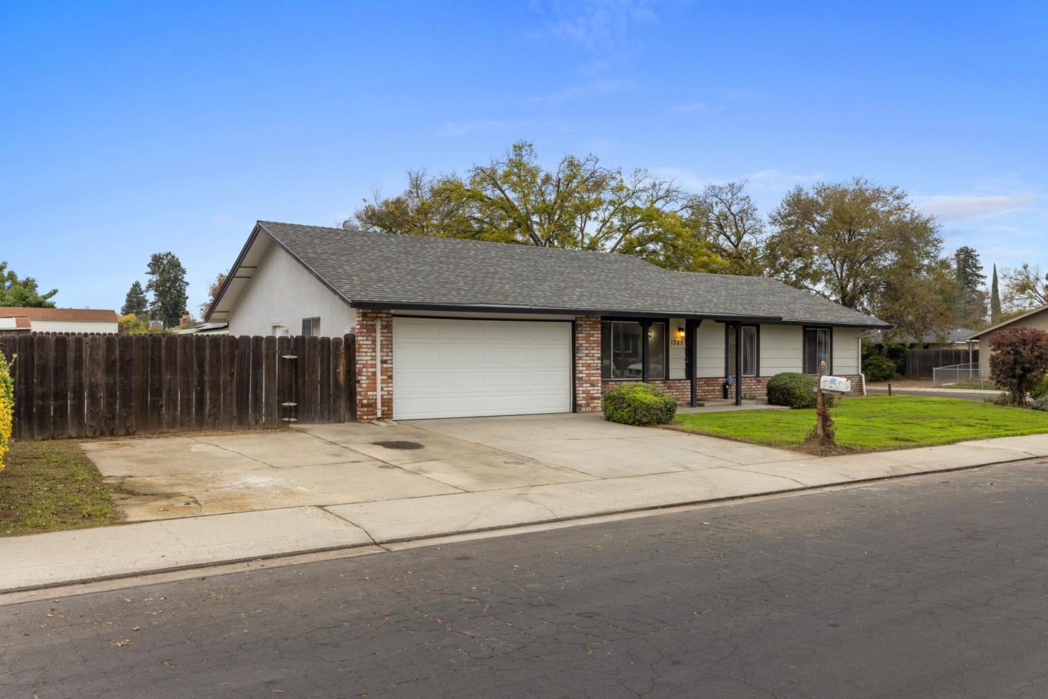 1205 Kara Lane Modesto, CA 95355 - Photo 2 of 39 a brick house next to a yard with wooden fence