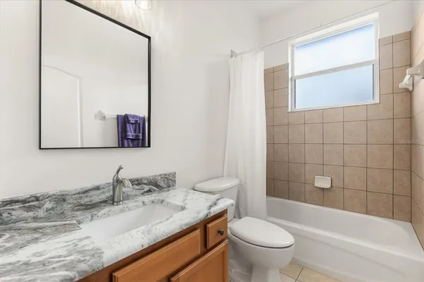 a bathroom with a granite countertop toilet a sink and a mirror