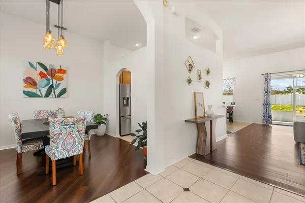 a view of a dining room with furniture one side kitchen view and wooden floor