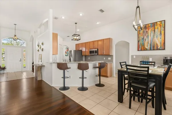 a kitchen with stainless steel appliances kitchen island granite countertop a table chairs and a refrigerator