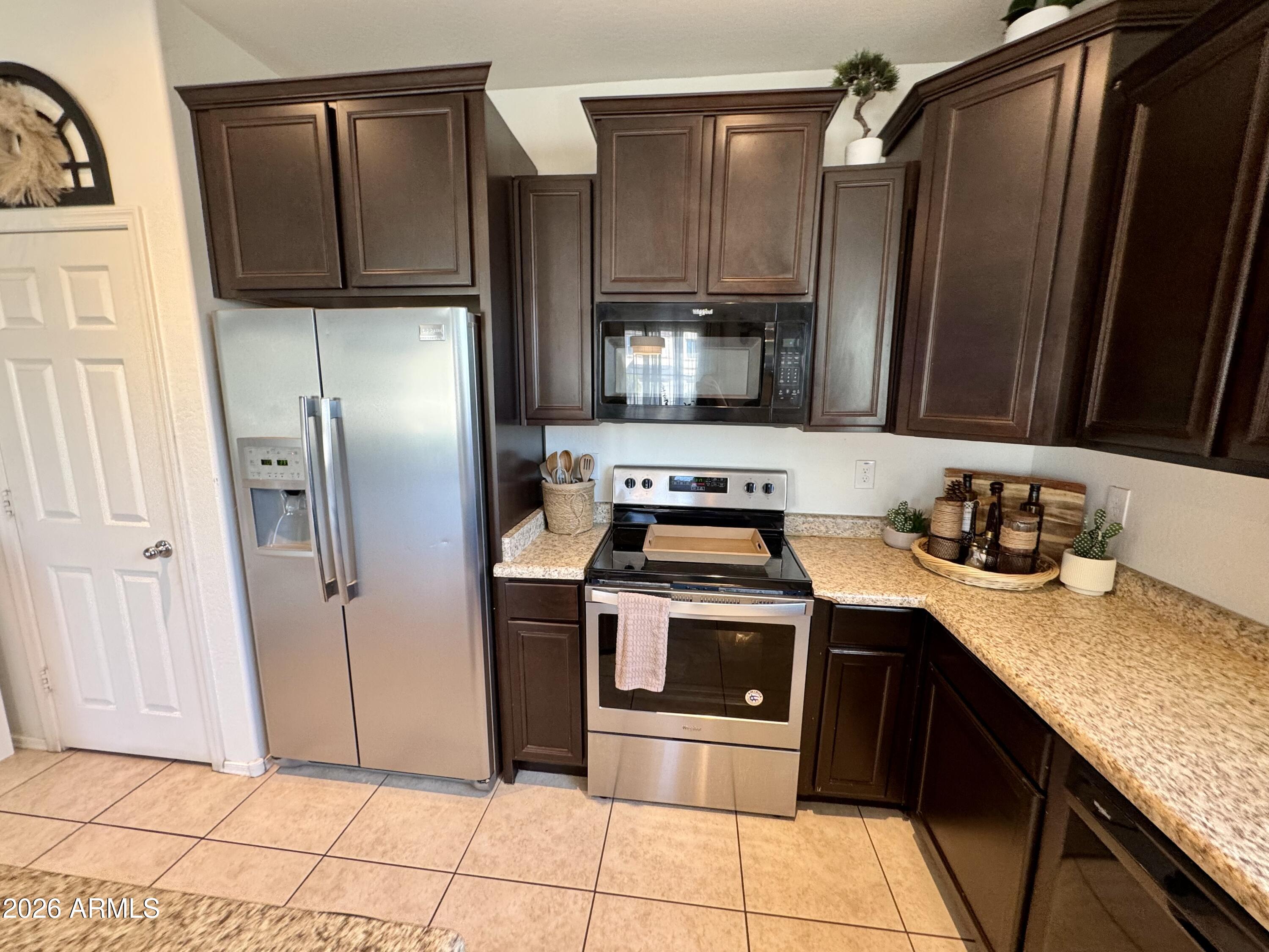 12202 West Del Rio Lane Avondale, AZ 85323 - Photo 9 of 60 a kitchen with stainless steel appliances granite countertop a refrigerator a stove and sink