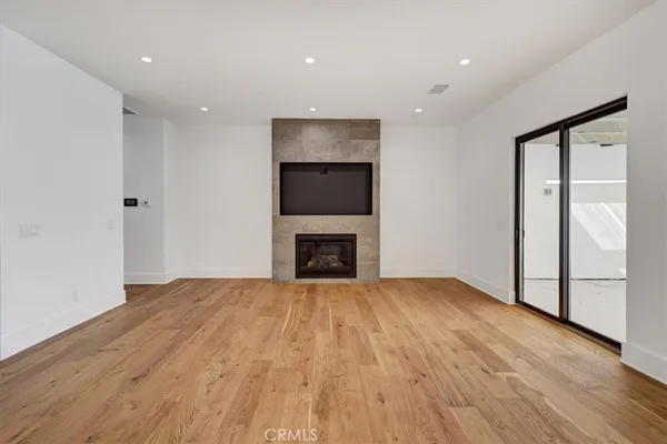 a view of an empty room with wooden floor and a fireplace
