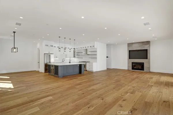 a large white kitchen with kitchen island a sink stainless steel appliances and cabinets