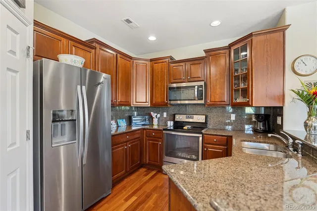 a kitchen with stainless steel appliances granite countertop a refrigerator a stove top oven a sink and dishwasher