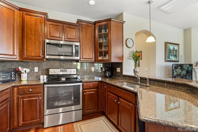 a kitchen with stainless steel appliances granite countertop a sink a stove and cabinets