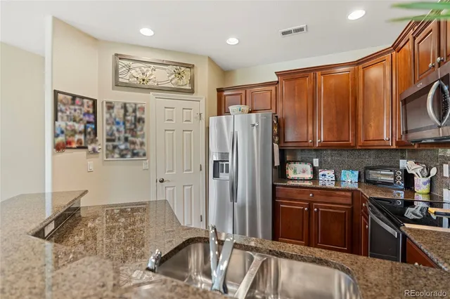 a kitchen with stainless steel appliances granite countertop a refrigerator and a sink