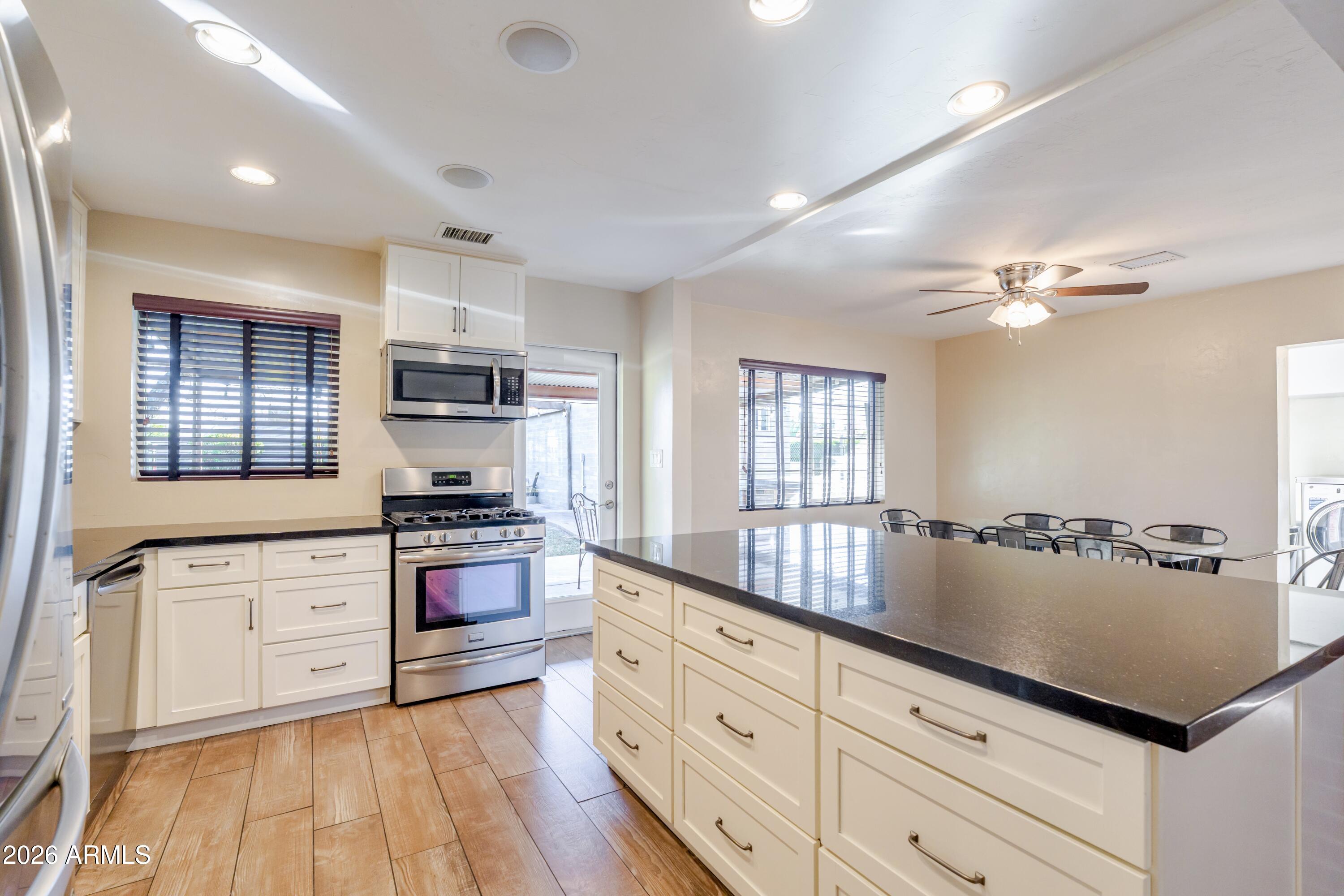 1631 West Rovey Avenue Phoenix, AZ 85015 - Photo 13 of 46 a large kitchen with cabinets wooden floor and stainless steel appliances