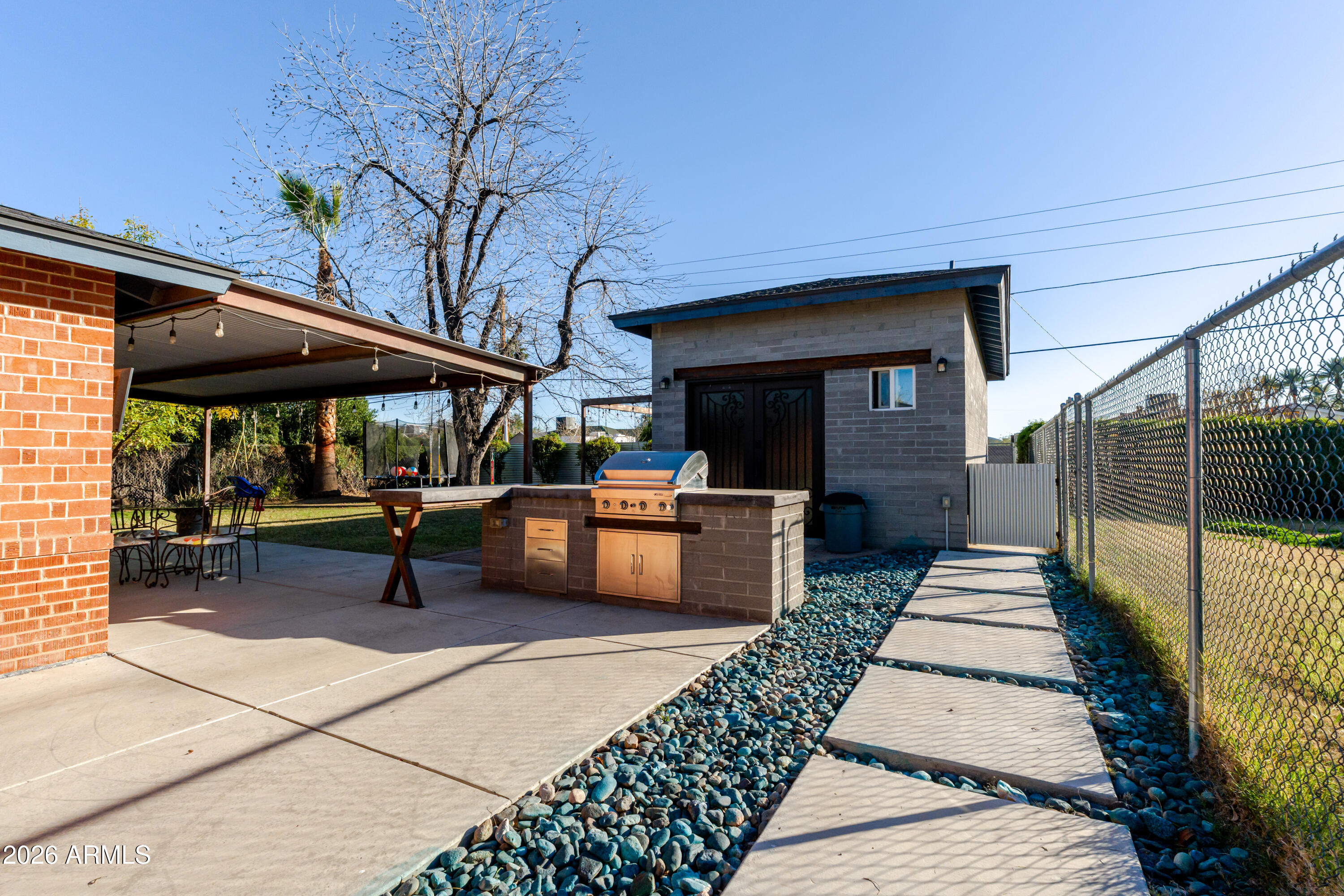 1631 West Rovey Avenue Phoenix, AZ 85015 - Photo 32 of 46 a view of a patio with table and chairs under an umbrella with a barbeque