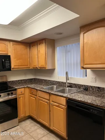 a kitchen with granite countertop cabinets stainless steel appliances a sink and a window