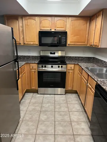 a kitchen with stainless steel appliances granite countertop a stove a sink and a microwave