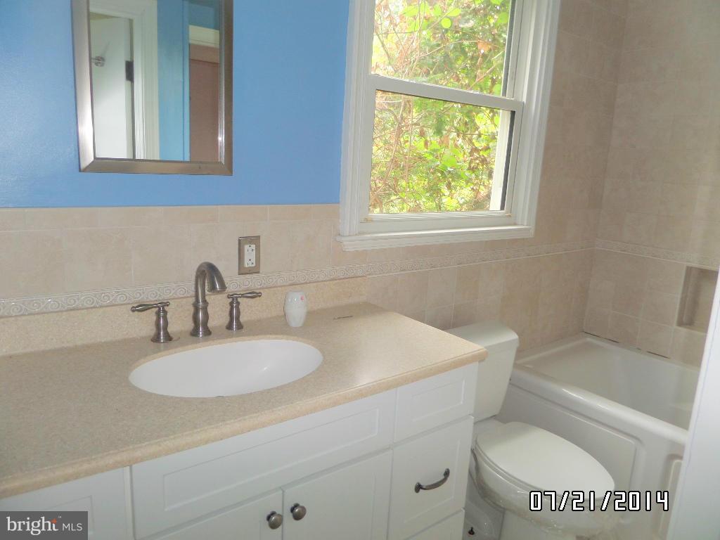 608 Cliveden Road Baltimore, MD 21208 - Photo 11 of 23 a bathroom with a toilet a sink a mirror and a window