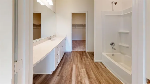 a spacious bathroom with a tub double vanity sink and mirror