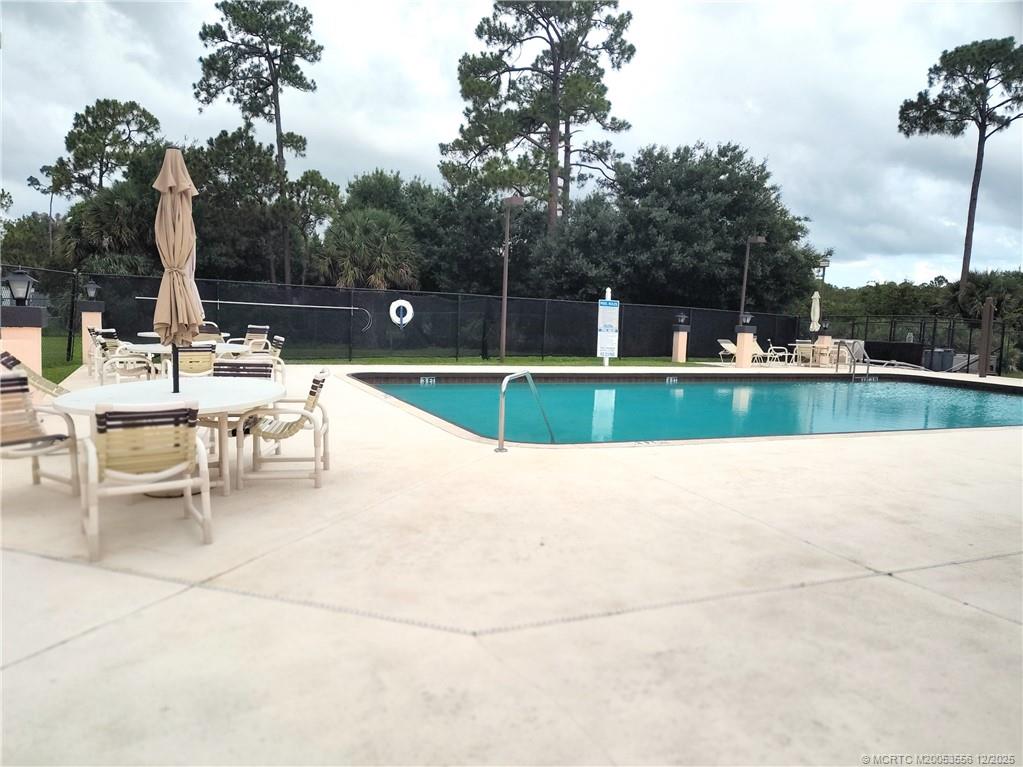 2581 Southwest Pontiac Place Stuart, FL 34997 - Photo 58 of 62 a view of a swimming pool with a bench and trees in the background