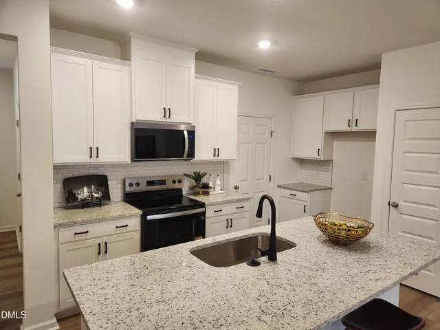 a kitchen with stainless steel appliances granite countertop a sink a stove and a refrigerator
