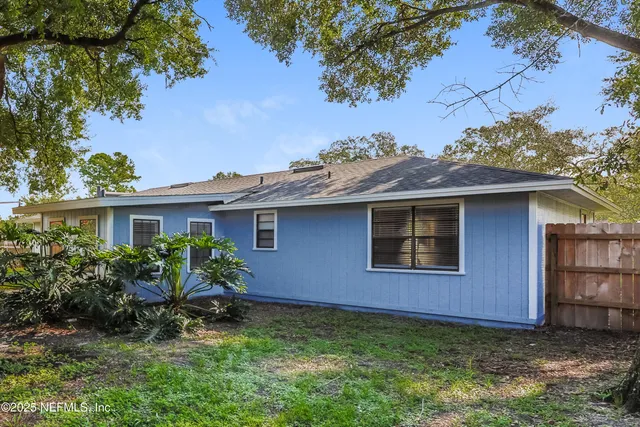 a view of a house with a yard plants and large tree