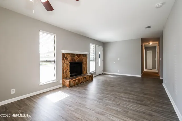 a view of an empty room with window and wooden floor