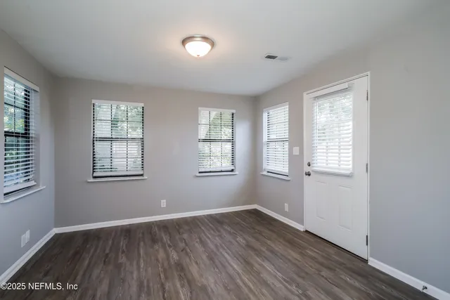 an empty room with wooden floor and windows