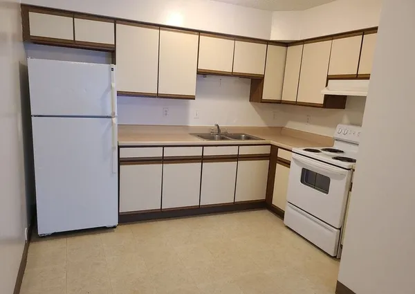 a kitchen with stainless steel appliances granite countertop white cabinets a sink a stove a refrigerator and cabinets