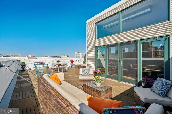 a view of roof deck with dining table and couches chairs with wooden floor