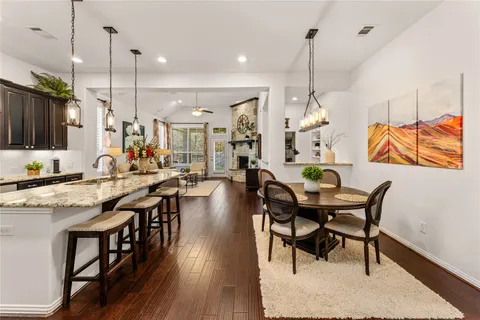 a dining table chairs wooden floor and a chandelier