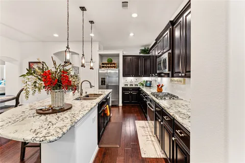 a kitchen with stainless steel appliances kitchen island granite countertop a stove a sink and a refrigerator