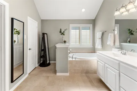 a spacious bathroom with a tub sink and mirror