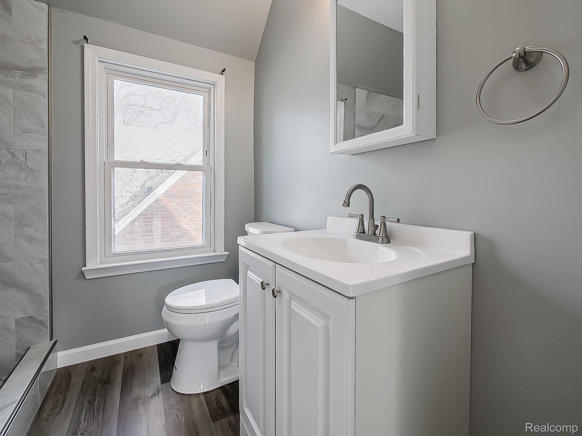 13 Mohawk Road Pontiac, MI 48341 - Photo 18 of 24 Full bathroom featuring vanity, dark wood-style floors, a baseboard radiator, and a shower
