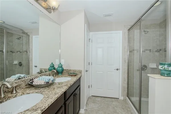a bathroom with a granite countertop sink a mirror and a shower