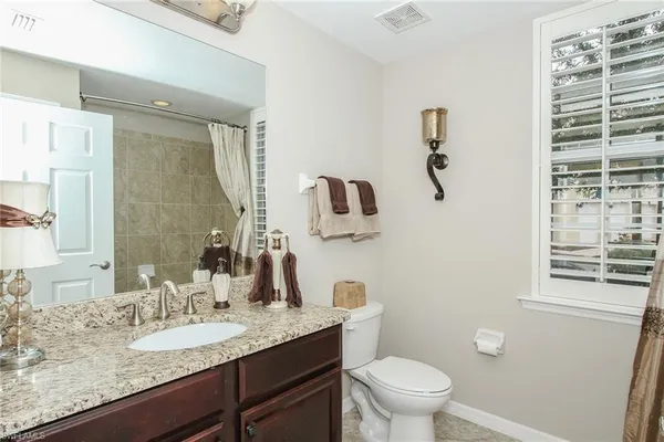 a bathroom with a granite countertop sink a toilet and a mirror