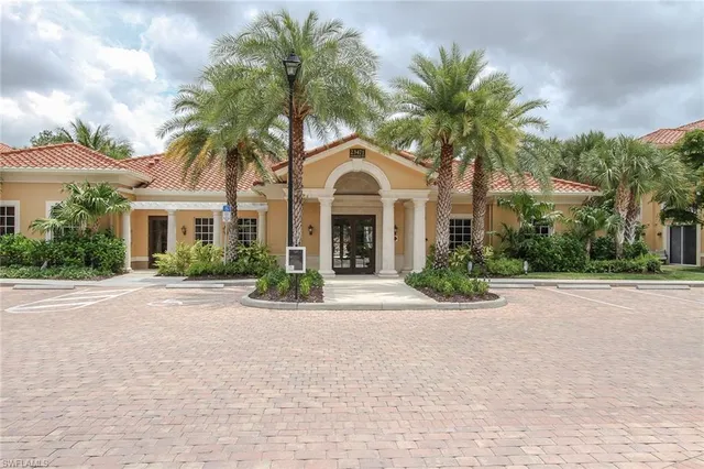 front view of a house with a yard and palm trees