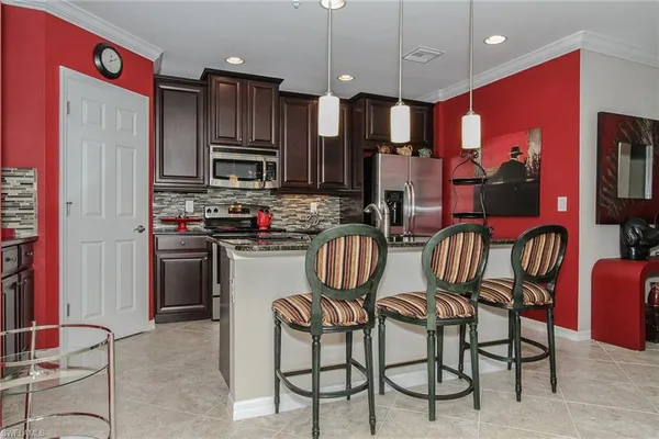 a kitchen with granite countertop a stove a sink a dining table and chairs
